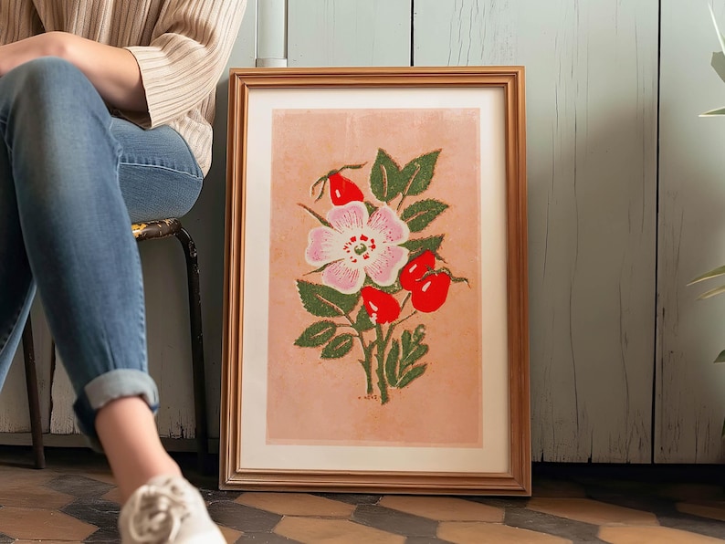 May include: A framed print of a pink and white flower with red berries and green leaves on a light pink background.