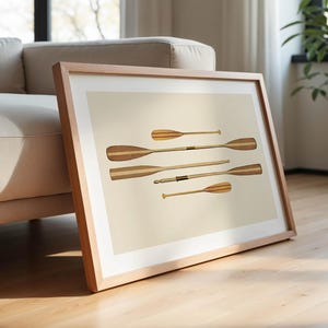 May include: A framed print featuring six wooden oars with a light beige background. The oars vary in size and have a light and dark wood grain pattern. The frame is made of light-colored wood.