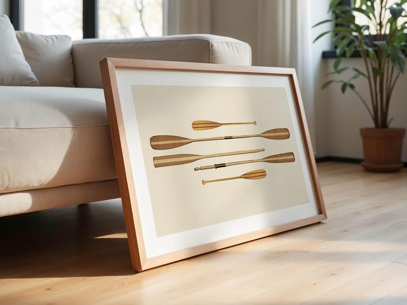 May include: A framed print featuring six wooden oars with a light beige background. The oars vary in size and have a light and dark wood grain pattern. The frame is made of light-colored wood.