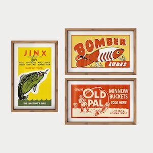 May include: Three framed vintage fishing lure advertisements. The top right poster reads "Bomber Lures" with a red and white lure illustration. The bottom right poster says "Old Pal Minnow Buckets". The left poster says "Jinx for Bass, Walleyes and other fresh and salt water fish".