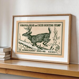 May include: Framed vintage print of a deer leaping over a log, labeled "Virginia Bear and Deer Hunting Stamp." The artwork is in shades of green and brown, with text indicating it's for nonresident hunters from 1945-46.