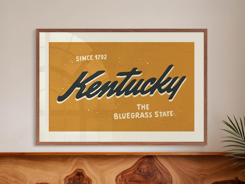 May include: A vintage-style poster with a yellow background and white text that reads "Since 1792 Kentucky The Bluegrass State". The word "Kentucky" is written in a large, stylized black font.