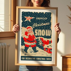 Op de afbeelding: Een vintage kerstboomversiering met een rode en witte kerstman die een zak sneeuw vasthoudt. De tekst luidt "Fireproof Christmas Snow" en "For Decorating Christmas Trees".