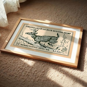 May include: Framed vintage print of a deer hunting stamp. The artwork features a detailed illustration of a deer leaping over a log, with text that reads "VIRGINIA BEAR and DEER HUNTING STAMP" and "NONRESIDENT 1945-46". The frame is made of light-colored wood.