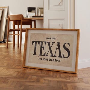 May include: A framed print with a vintage aesthetic featuring the word "TEXAS" in bold black letters. The text "Since 1845" and "The Lone Star State" are also included in the print.