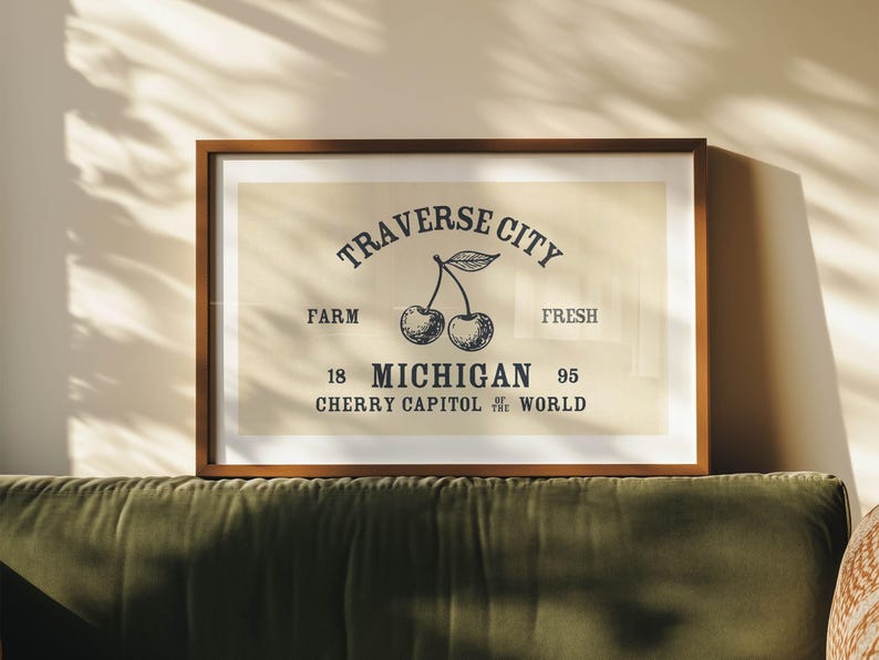 May include: Framed print featuring a vintage-style design with the text "Traverse City" above a cherry illustration. The text includes "Farm," "Fresh," "18 Michigan 95," and "Cherry Capital of the World."