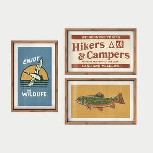 May include: Three framed art prints with a nature theme. One print says "Enjoy the Wildlife" with a duck graphic. Another says "Hikers & Campers" with text about preserving land. The third print features a fish.