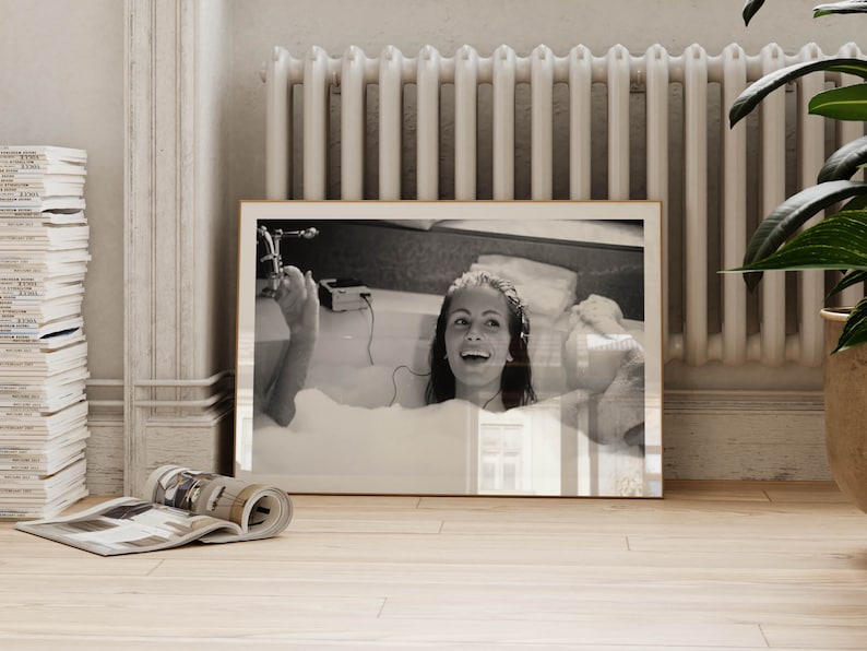 Peut inclure: Une photographie en noir et blanc d'une femme dans une baignoire, souriante et &eacute;coutant de la musique avec des &eacute;couteurs. La photo est encadr&eacute;e dans un cadre en bois.
