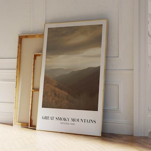 Op de afbeelding: Een ingelijste poster met een foto van een bergketen met een bewolkte lucht. De poster heeft de tekst "Great Smoky Mountains National Park" onderaan.