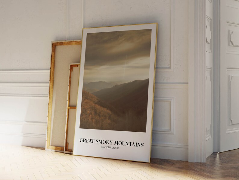 Op de afbeelding: Een ingelijste poster met een foto van een bergketen met een bewolkte lucht. De poster heeft de tekst "Great Smoky Mountains National Park" onderaan.