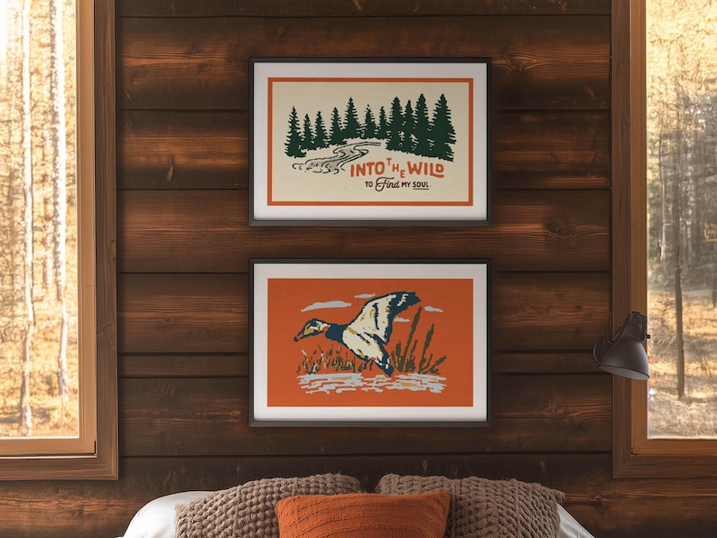 May include: Two framed art prints with nature themes hang on a wood-paneled wall. The top print features a forest scene with the text "Into the Wild to Find My Soul." The bottom print shows a duck in flight.