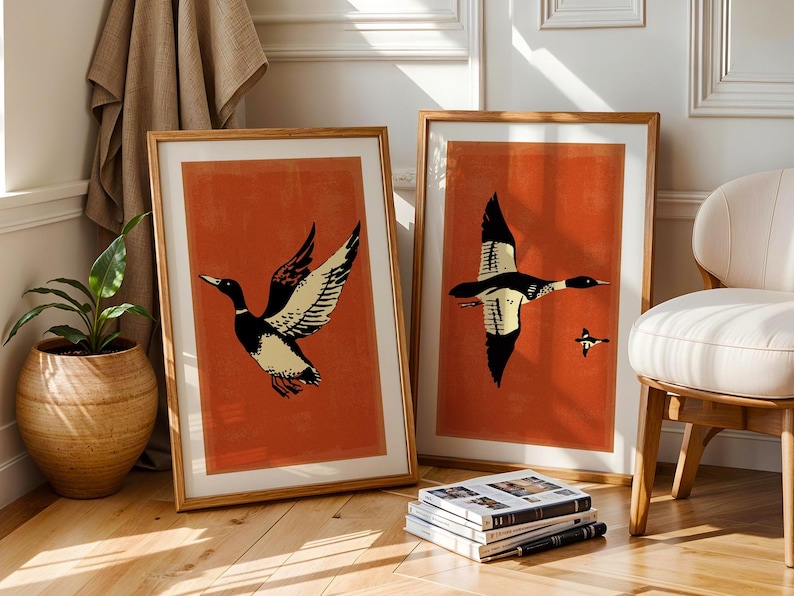 May include: Two framed prints of stylized black and white ducks on a burnt orange background. The ducks are flying in different directions.