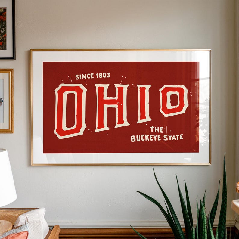 K&ouml;nnte beinhalten: Ein Vintage-Druck in Rot und Wei&szlig; mit dem Wort "OHIO" und dem Text "Since 1803" und "The Buckeye State" in einem goldenen Rahmen.