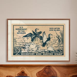 Pode incluir: Um cartaz de estilo vintage para um selo de ca&ccedil;a a aves migrat&oacute;rias. O cartaz apresenta uma ilustra&ccedil;&atilde;o azul e branca de tr&ecirc;s patos voando sobre um corpo de &aacute;gua. O texto no cartaz diz "U.S. Department of the Interior", "Void After June 30, 1952", e "$2 Selo de ca&ccedil;a a aves migrat&oacute;rias".