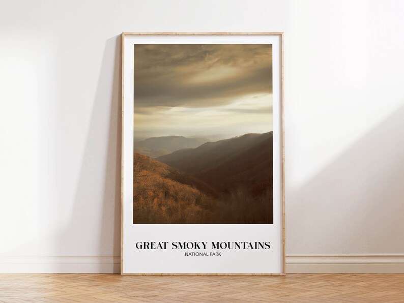 Op de afbeelding: Een ingelijste print van een landschapsfoto van het Great Smoky Mountains National Park. De afbeelding toont een mistige, goudkleurige bergketen met een bewolkte lucht.
