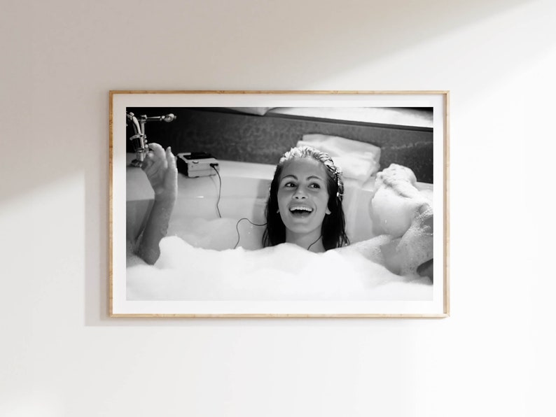 Peut inclure: Une photographie en noir et blanc d'une femme dans une baignoire remplie de bulles. Elle sourit et &eacute;coute de la musique avec des &eacute;couteurs.