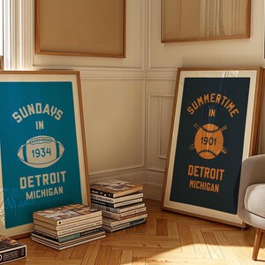 Peut inclure: Deux affiches encadr&eacute;es dans un sch&eacute;ma de couleurs bleu et blanc. L'affiche de gauche dit "Sundays in Detroit Michigan 1934" avec un graphique de football. L'affiche de droite dit "Summertime in Detroit Michigan 1901" avec un graphique de baseball.