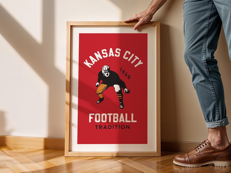 May include: A framed poster with a red background and white text that reads "Kansas City 1960 Football Tradition". A vintage illustration of a football player in a helmet and uniform is in the center of the poster.