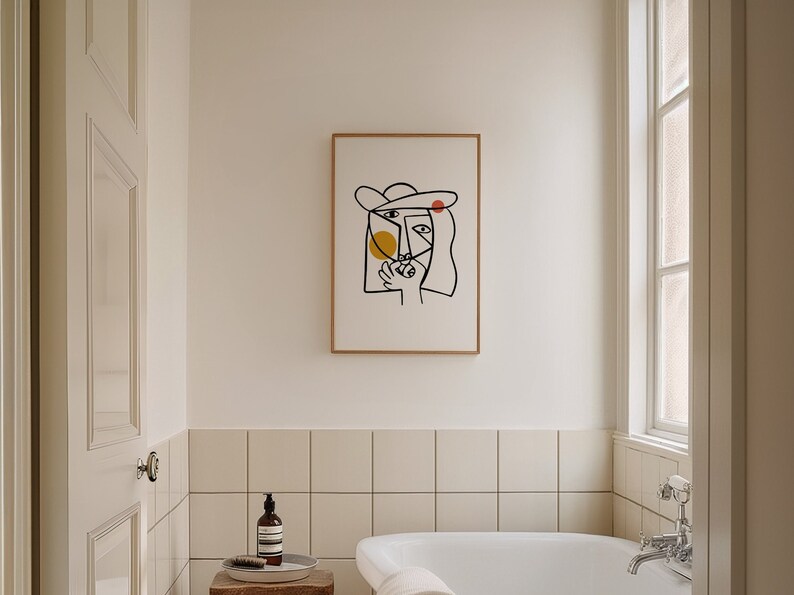May include: A framed black and white line drawing of a person's face with a hat. The drawing is on a white background and has yellow and red circles.