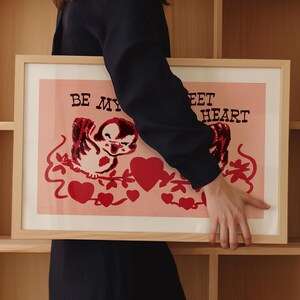 May include: A framed print with a pink background and a cartoon bird with red hearts and the text "Be My Sweet Heart".