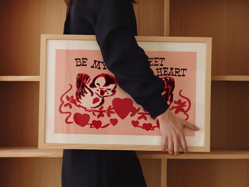 May include: A framed print with a pink background and a cartoon bird with red hearts and the text "Be My Sweet Heart".