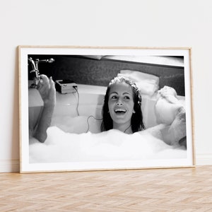 Peut inclure: Une photographie en noir et blanc d'une femme dans une baignoire, souriante et &eacute;coutant de la musique sur un lecteur cassette.