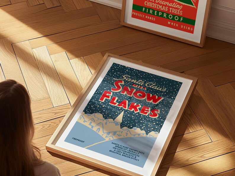 May include: A vintage-style poster with a blue background and white snowflakes. The poster features the text "Santa Claus's Snowflakes" in red and white lettering. The poster is framed in a light wood frame.