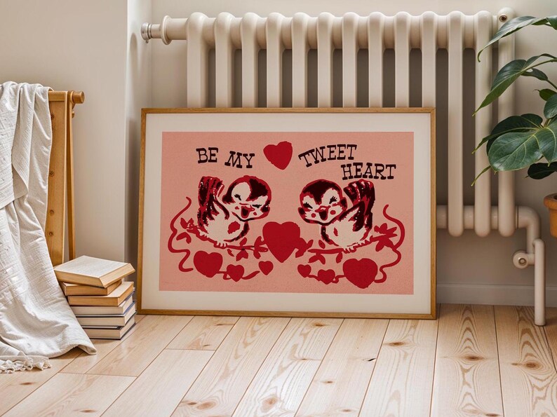 May include: A pink and red Valentine's Day print with two cartoon birds on a branch. The birds are holding a heart between them. The text reads "Be My Tweet Heart".