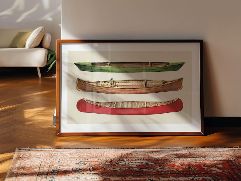 May include: Framed art print featuring three canoes in green, brown, and red. The boats are depicted in a detailed, illustrative style, showcasing their shape and design. The artwork is displayed on a wooden floor.