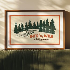 Puede incluir: Una impresi&oacute;n enmarcada con una est&eacute;tica vintage que presenta una escena de bosque con un r&iacute;o sinuoso y el texto "INTO THE WILD TO FIND MY SOUL."