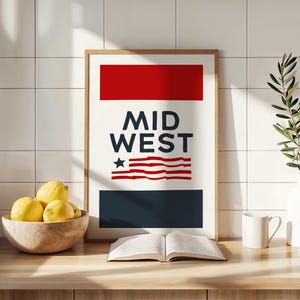 May include: A framed print with a red, white, and blue design. The print says "MID WEST" and features a stylized American flag. The print is on a wooden countertop with a bowl of lemons, a book, a white mug, and a vase with a green plant.