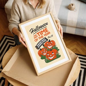 May include: A framed Halloween poster with a light wood frame. The poster features three smiling orange pumpkins and the text "Halloween, the best time of the year, Oct. 31". The words "Pumpkin Patch Jamboree" are also included.