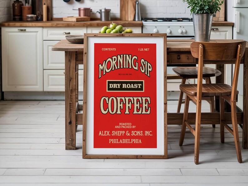 May include: A framed vintage-style coffee advertisement with a red background and cream-coloured text. The text reads "MORNING SIP DRY ROAST COFFEE" and includes the weight as 0.45 kg net. The frame is made of wood. The image is displayed in a kitchen setting.