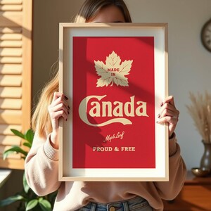 Op de afbeelding: Ingelijste print met een rode achtergrond en de woorden "Made in Canada" in cr&egrave;mekleurige letters. Een esdoornblad staat boven het woord "Canada". De zin "Proud & Free" staat eronder.
