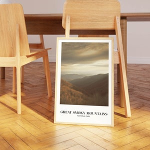 Op de afbeelding: Een ingelijste print van een schilderachtig uitzicht op het Great Smoky Mountains National Park. De afbeelding toont een bergketen met een bewolkte lucht op de achtergrond. De tekst "Great Smoky Mountains National Park" is onder de afbeelding gedrukt.