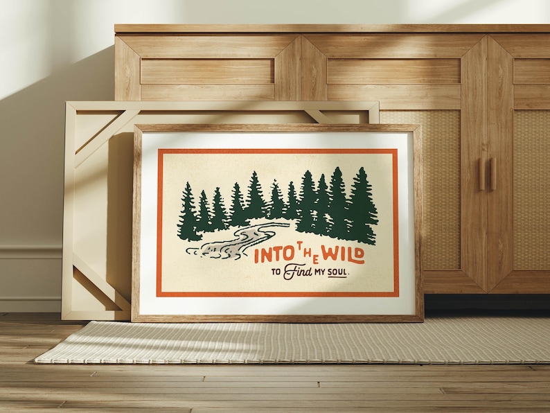 Puede incluir: Una impresi&oacute;n enmarcada con una est&eacute;tica vintage que presenta una ilustraci&oacute;n estilizada de un r&iacute;o que fluye a trav&eacute;s de un bosque. El texto dice "Into the Wild to Find My Soul".