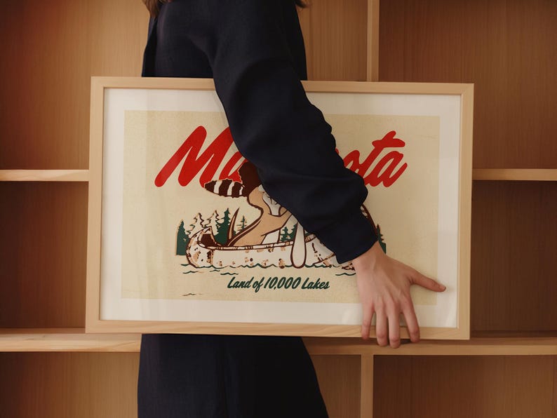 May include: A framed print with a vintage illustration of a canoe on a lake with the text "Minnesota Land of 10,000 Lakes" in red and black lettering.