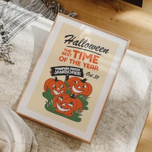 May include: Framed Halloween poster with a vintage design. The poster features the text "Halloween, the best time of the year" and "Pumpkin Patch Jamboree Oct. 31" with illustrations of smiling orange pumpkins. The frame is a light brown color.
