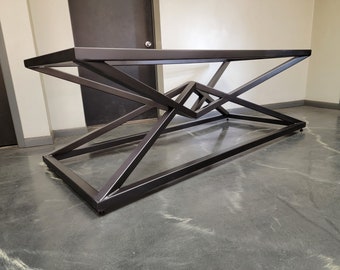 May include: A black metal table with a geometric, X-shaped base. The table is made of thick, sturdy metal and has a sleek, modern design.