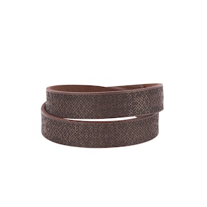 Peut inclure: Un bracelet en cuir marron avec un motif géométrique.
