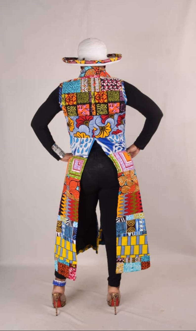 Puede incluir: Un chaleco largo y colorido con un dise&ntilde;o de patchwork. El chaleco tiene un cuello en V profundo y un dobladillo largo y fluido. El chaleco est&aacute; hecho de una variedad de telas, incluyendo algod&oacute;n y seda. El chaleco se lleva sobre una camisa negra de manga larga y pantalones negros. La persona lleva un sombrero blanco de ala ancha.
