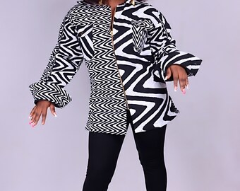 May include: A black and white patterned shirt with a zip fastening. The shirt has long sleeves with a wide cuff and a relaxed fit. The model is wearing black leggings and red heels.