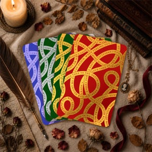 May include: Four square cards with text in a vintage style, in blue, green, yellow, and red. The cards have gold text with phrases like "Love Thee" and "My Child". The image includes a candle, a quill, dried flowers, and a necklace.