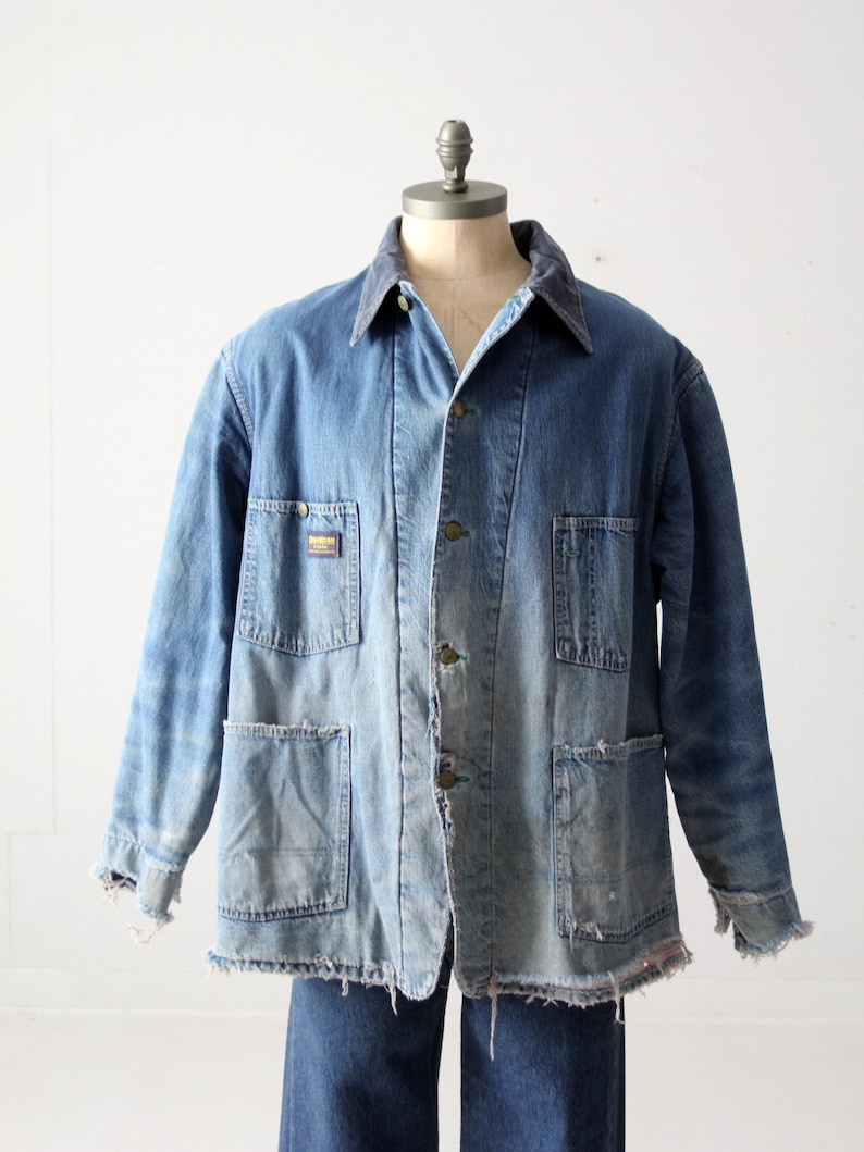 K&ouml;nnte beinhalten: Eine Vintage-Jeansjacke mit Cordkragen, in verblasster blauer Farbe und mit ausgefransten Kanten. Die Jacke hat mehrere Taschen und einen Knopfverschluss.