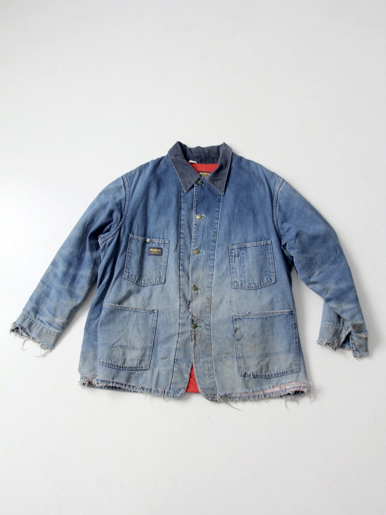 K&ouml;nnte beinhalten: Eine vintage blaue Jeansjacke mit rotem Flanellfutter. Die Jacke hat einen Knopfschlie&szlig;er, zwei Brusttaschen und zwei untere Taschen. Die Jacke ist abgenutzt und hat einen ausgefransten Saum.