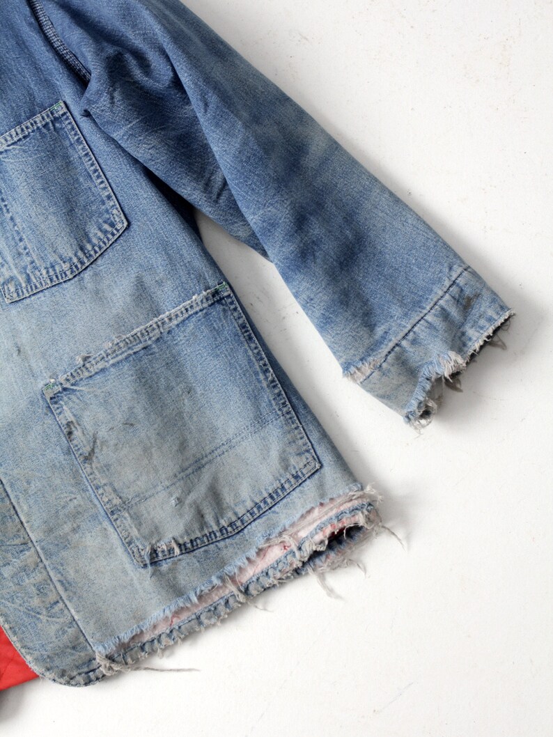 K&ouml;nnte beinhalten: Eine Vintage-Jeansjacke mit ausgefransten Kanten und einer aufgesetzten Tasche. Die Jacke ist hellblau und hat einen abgenutzten Look.