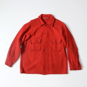 May include: A red long-sleeved shirt with a button-up front and two large pockets. The shirt is made of a thick, textured fabric.
