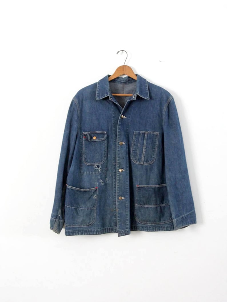 K&ouml;nnte beinhalten: Eine vintage blaue Jeans-Arbeitsjacke mit mehreren Taschen und einem Knopfverschluss.