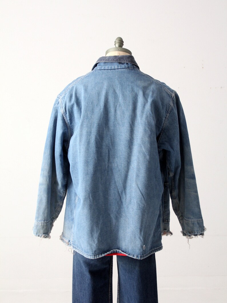 K&ouml;nnte beinhalten: Eine blaue Jeansjacke mit einem Cordkragen. Die Jacke hat einen abgenutzten Look und ausgefranste Kanten.