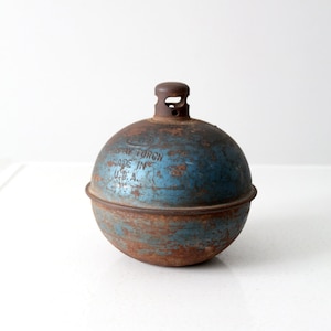 May include: A vintage metal torch in blue and brown, spherical in shape. The torch shows signs of rust and bears the text "CLAY TORCH MADE IN U.S.A.". It features a small, cylindrical nozzle at the top.